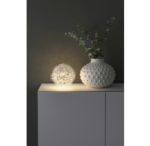 Dekorativ scen med sfärisk lampa och vas på ett skåp