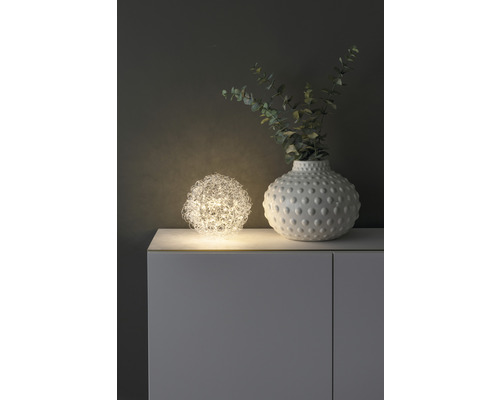 Dekorativ scen med sfärisk lampa och vas på ett skåp