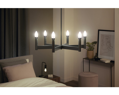 Modern rumsvy med en svart ljuskrona med flera lampor ovanför en säng