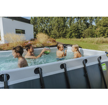 Familj med barn leker i rektangulär pool i trädgården.