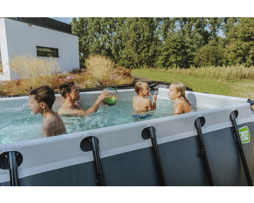 Familj med barn leker i rektangulär pool i trädgården.