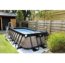 Rektangulär pool med träpanel, stege och filterpump i trädgården.