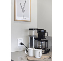 Kaffebryggare med två koppar på ett underlägg av trä i ett kök
