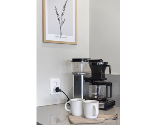 Kaffebryggare med två koppar på ett underlägg av trä i ett kök