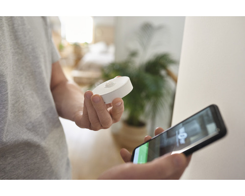 En person håller en rörelsesensor och en smartphone i handen.
