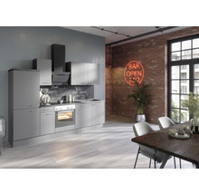 Modernt kök med grå skåp, fläkt och matbord i en loftliknande miljö med tegelvägg.