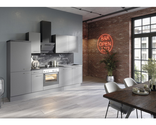 Modernt kök med grå skåp, fläkt och matbord i en loftliknande miljö med tegelvägg.