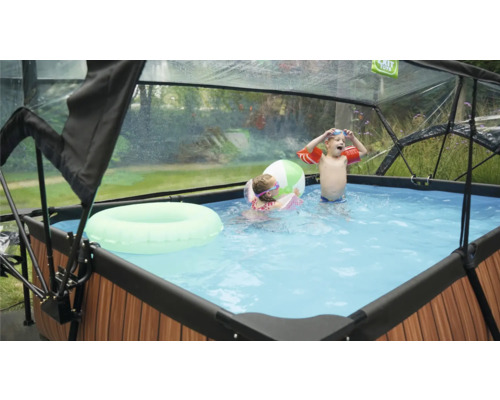 Pool med tak, barn som leker med badring och boll i vattnet
