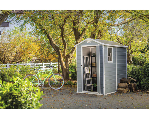 Trädgårdsscen med redskapsbod, cykel, stege, hylla och vedstapel