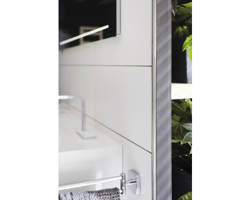 Detaljvy av ett badrum med handfat, handdukshållare, spegel och växter