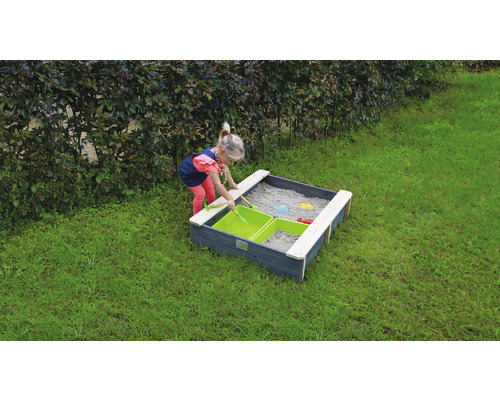 Barn leker i en sandlåda med träkant och sandleksaker i trädgården.