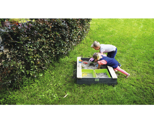 Två barn leker i en sandlåda i trädgården.