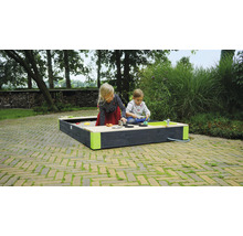 Två barn leker i en sandlåda med vattenlekplats i trädgården.