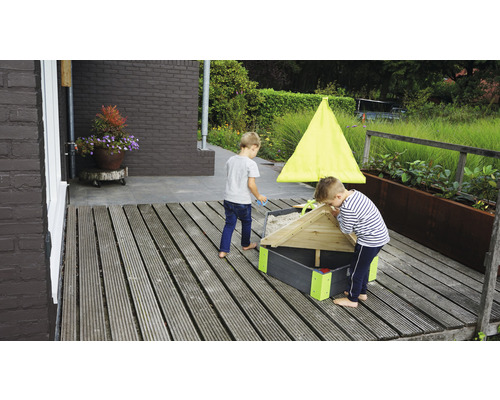 Två barn leker i en sandlåda med tak på en träaltan.