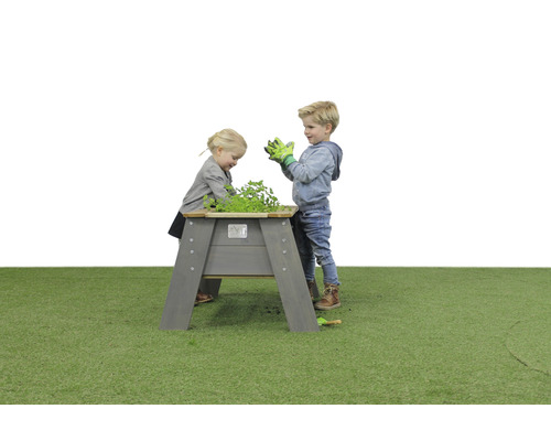 Barn leker med en upphöjd trädgårdsbädd i trä i trädgården.