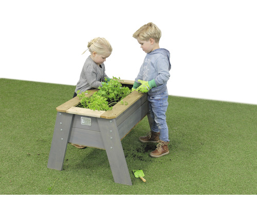 Två barn trädgårdssköter i en upphöjd träbädd i trädgården.