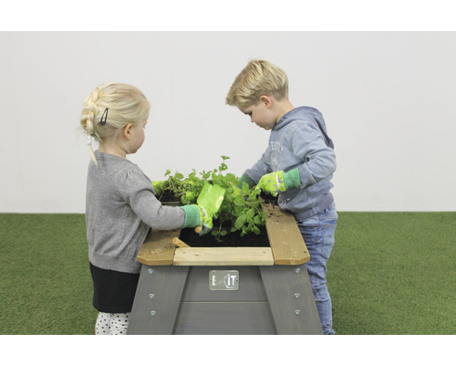 Två barn leker med en upphöjd trädgårdslåda i trädgården.