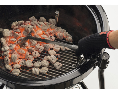 Grill med glödande briketter och grilltång