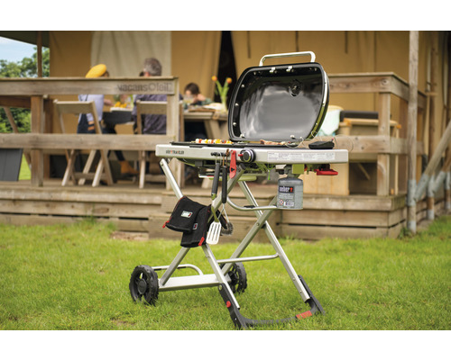 Weber Traveler gasolgrill med grillverktyg och gasflaska framför tältet