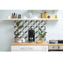 Köksscen med kaffebryggare, växter och köksredskap på hyllor