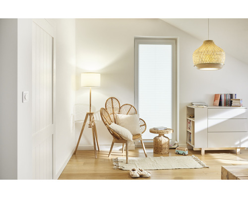 Ljust rum med rottingfåtölj, golvlampa och byrå