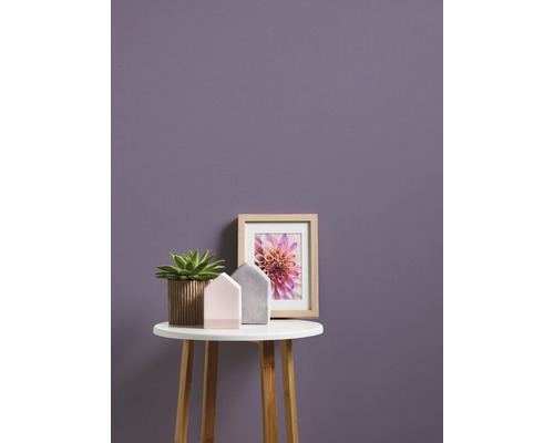 Dekorativ scen med krukväxt, husdekorationer och en inramad bild på ett litet bord framför en vägg