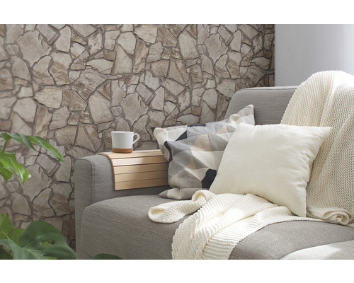 Vardagsrum med stenmur, soffa, kuddar, filt och kopp