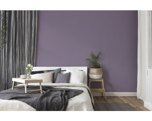 Sovrum med säng, trägolv och lila vägg