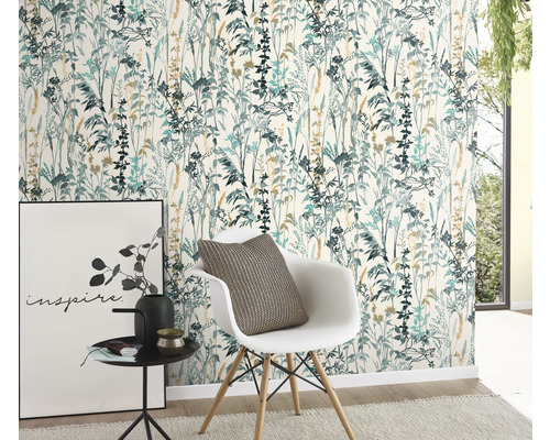 Ett rum med en blommig tapet i blågröna och beige toner, en vit stol med kudde, ett sidobord med dekoration och en tavla.