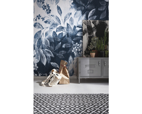 Rumsutsikt med blomstapet, metallskåp, målning, krukväxter och matta med geometriskt mönster