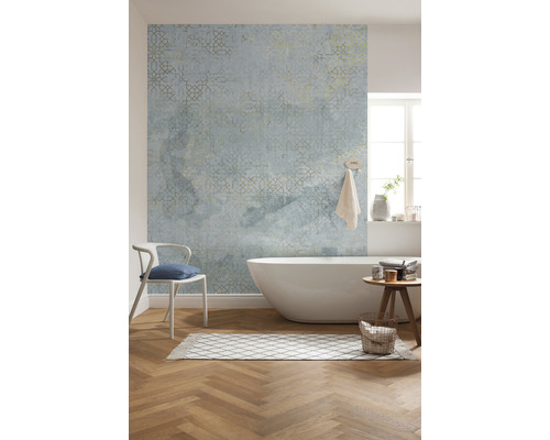 Badrum med badkar, stol, matta, pall och mönstrad tapet.