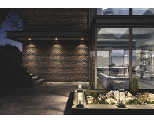 Utsida av ett modernt hus med murverk, trädgårdslyktor och infällda spotlights