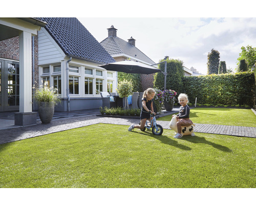 Trädgård med gräsmatta, trädgårdsmöbler och lekande barn