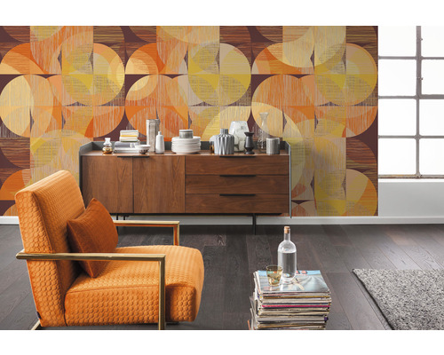 Vardagsrum med mönstrad tapet, byrå och fåtölj