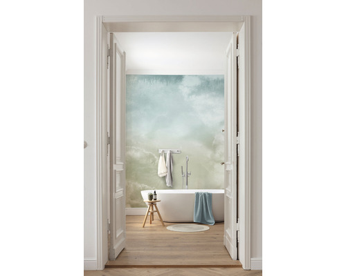 Ljust badrum med badkar, pall och tapet med molnmönster, sett genom en öppen dörr.