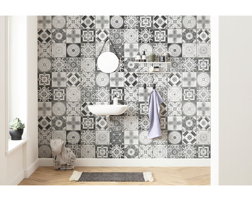 Badrum med handfat, spegel, hylla och väggplattor med ett ornamentalt mönster