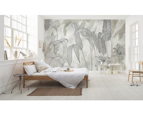 Ljust sovrum med en säng och en väggtapet med växtmotiv