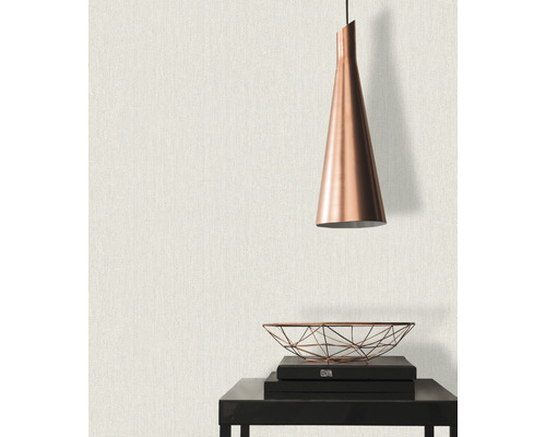 Närbild av en vägg med textilväv, kombinerat med en hängande lampa och dekorativa element på ett bord