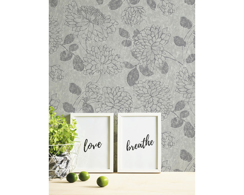 Tapet med blommönster, två tavelramar, krukväxt och limefrukter på ett bord