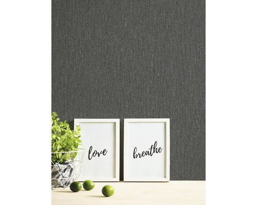 Närbild av en grå textil tapet med orden kärlek och andas i ramar, krukväxt och limefrukter