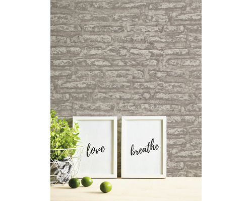 Vardagsrumsscen med tapet med tegelmönster, krukväxt och inramade affischer