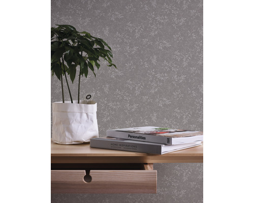 Bild av ett rum med en mönstrad tapet, ett bord med en växt och böcker