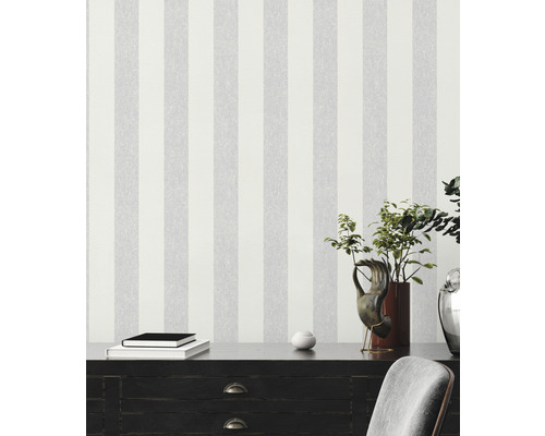 Scen med randig tapet, byrå, böcker och dekorationer för en modern inredning.