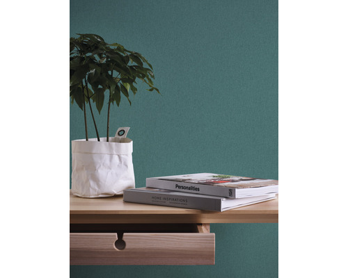 Dekorativ krukväxt i pappersbehållare med två böcker på ett träbord med låda