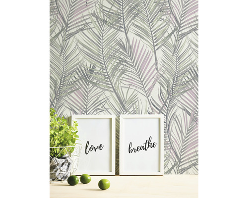 Scen med tapet med palmbladsmotiv, två tavelramar med inskriptionerna kärlek och andas, krukväxt och limefrukter