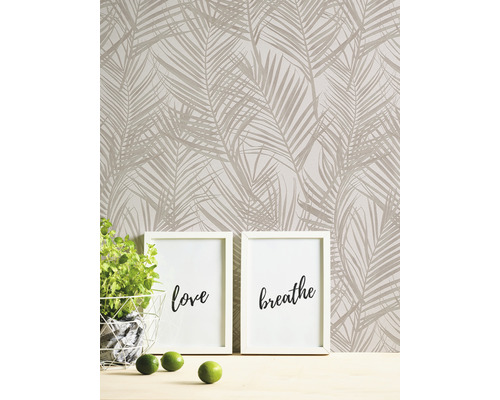 Vägg med tapet med palmträdsmönster, två fotoramar med inskriptionerna kärlek och andas