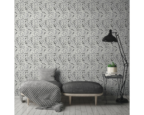 Ett rum med en blommig tapet, en bänk, en fåtölj, en golvlampa och ett sidobord