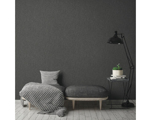 Grå textiltapet i sovrum med fåtölj, pall och golvlampa