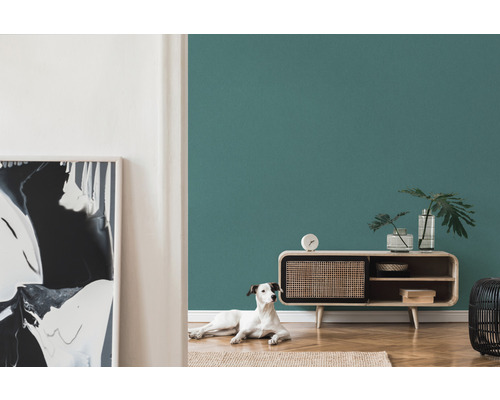 Vardagsrum med petroleumfärgad vägg, byrå och hund