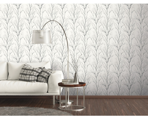 Vardagsrum med vit soffa och en vägg med tapet med grenmönster
